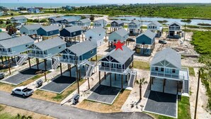 A coastal residential area with multiple houses, some elevated on stilts, and a parking lot. - Rare Community Pool! Walk to Beach! Pet Friendly (Bolivar Peninsula)