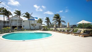 A swimming pool with lounge chairs and palm trees.