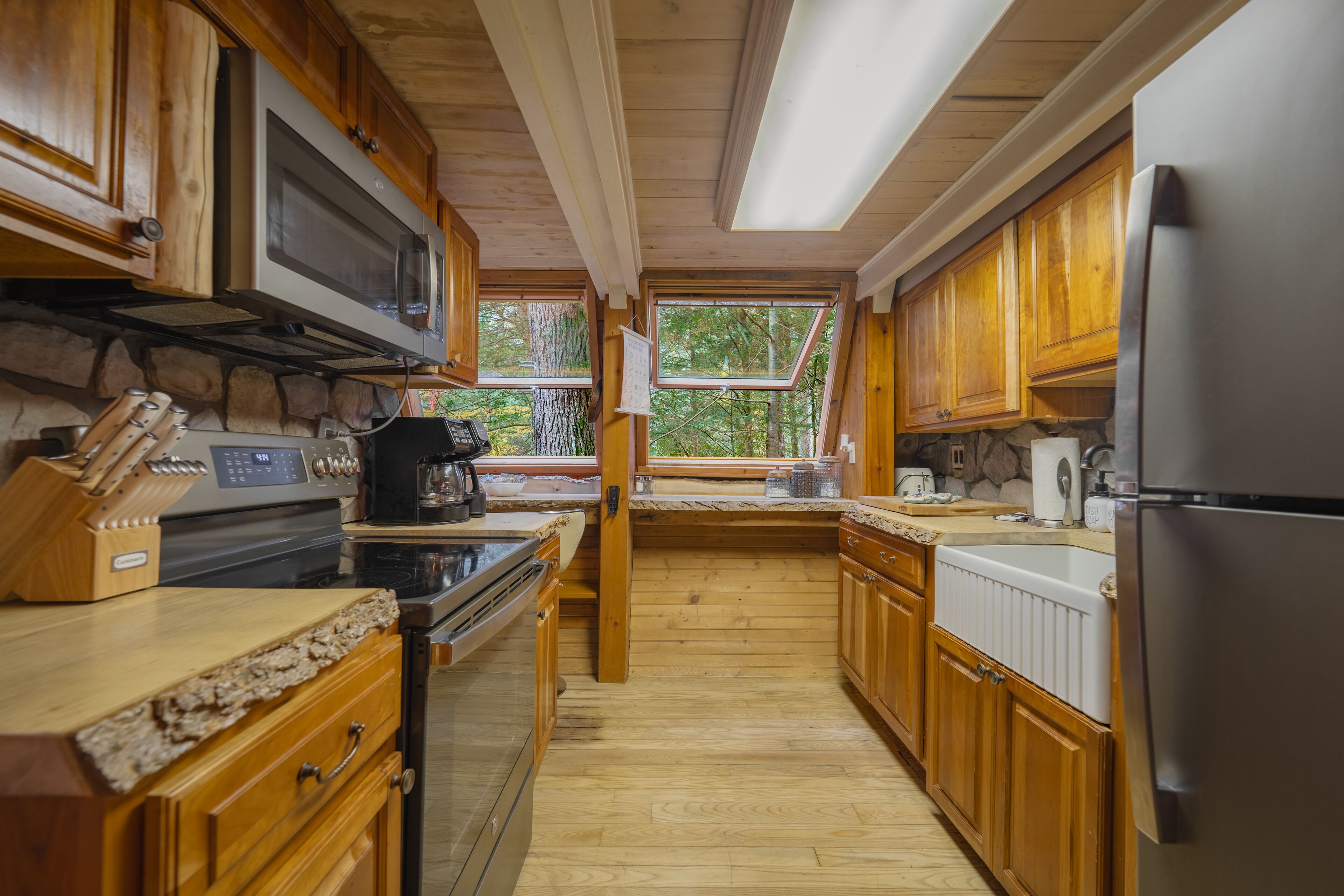 Une cuisine avec des meubles en bois, un réfrigérateur en acier inoxydable, une cuisinière et un four à micro-ondes.