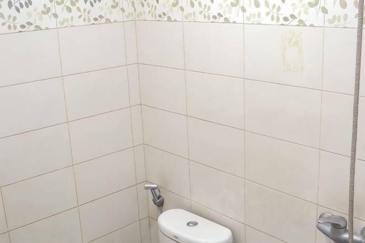 A bathroom with white tiles, a toilet, and a shower area.
