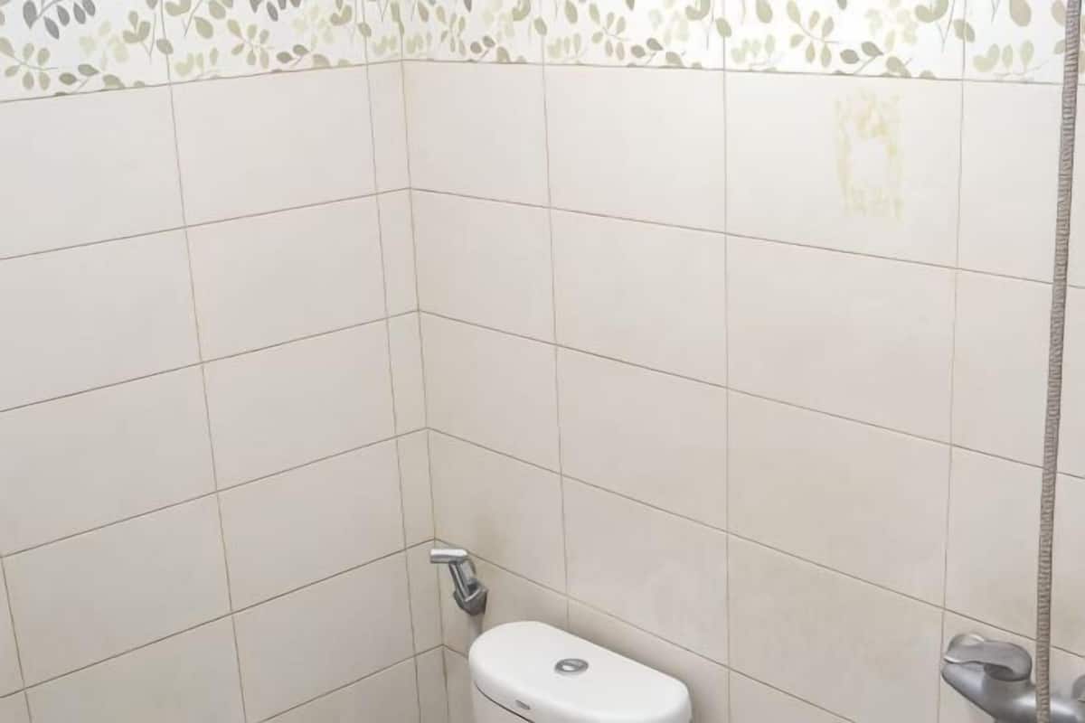 A bathroom with white tiles, a toilet, and a shower area.