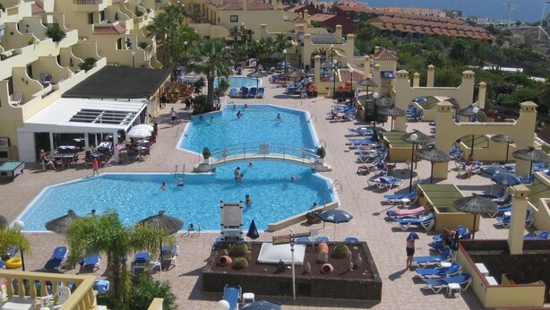 Un complejo turístico con varias piscinas, tumbonas y sombrillas.