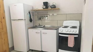 A compact kitchen with a refrigerator, sink, and stove.