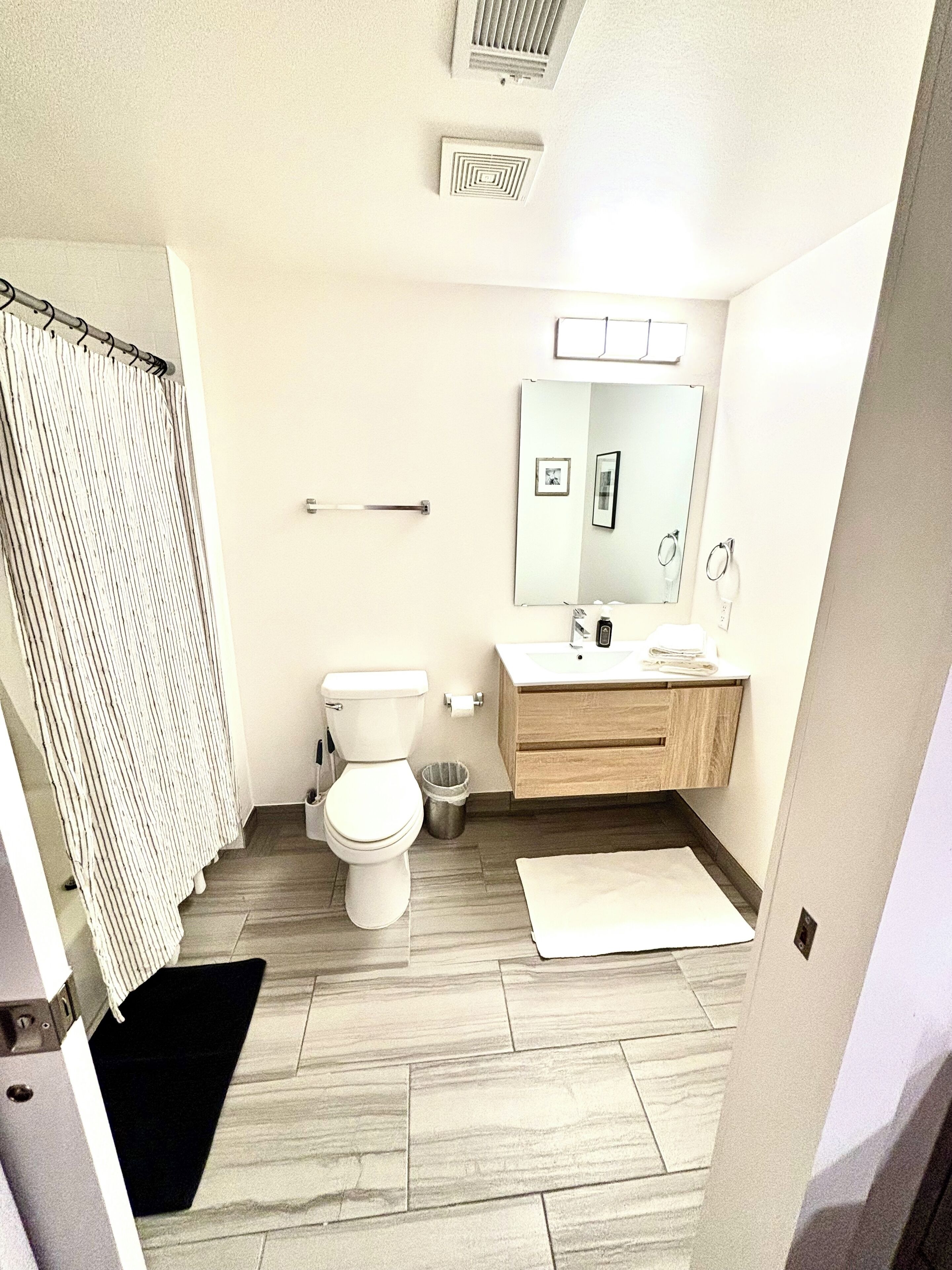 A bathroom with a toilet, sink, mirror, and shower curtain.