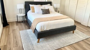A bedroom with a large bed, bedside tables, a window with a view, and a wardrobe. - Spacious Designer Apartment Downtown Tulsa-Gym Access (Tulsa)
