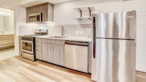 A modern kitchen with stainless steel appliances, a dishwasher, and wooden cabinets. - Spacious Designer Apartment Downtown Tulsa-Gym Access (Tulsa)