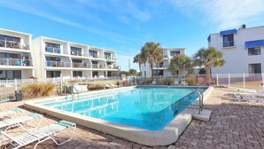 A rectangular swimming pool with a white deck, surrounded by lounge chairs and a white fence. - Ground floor unit! Close to pool and beach. (Saint George Island)