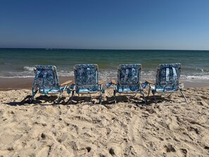 Four beach chairs with a floral pattern facing the ocean.