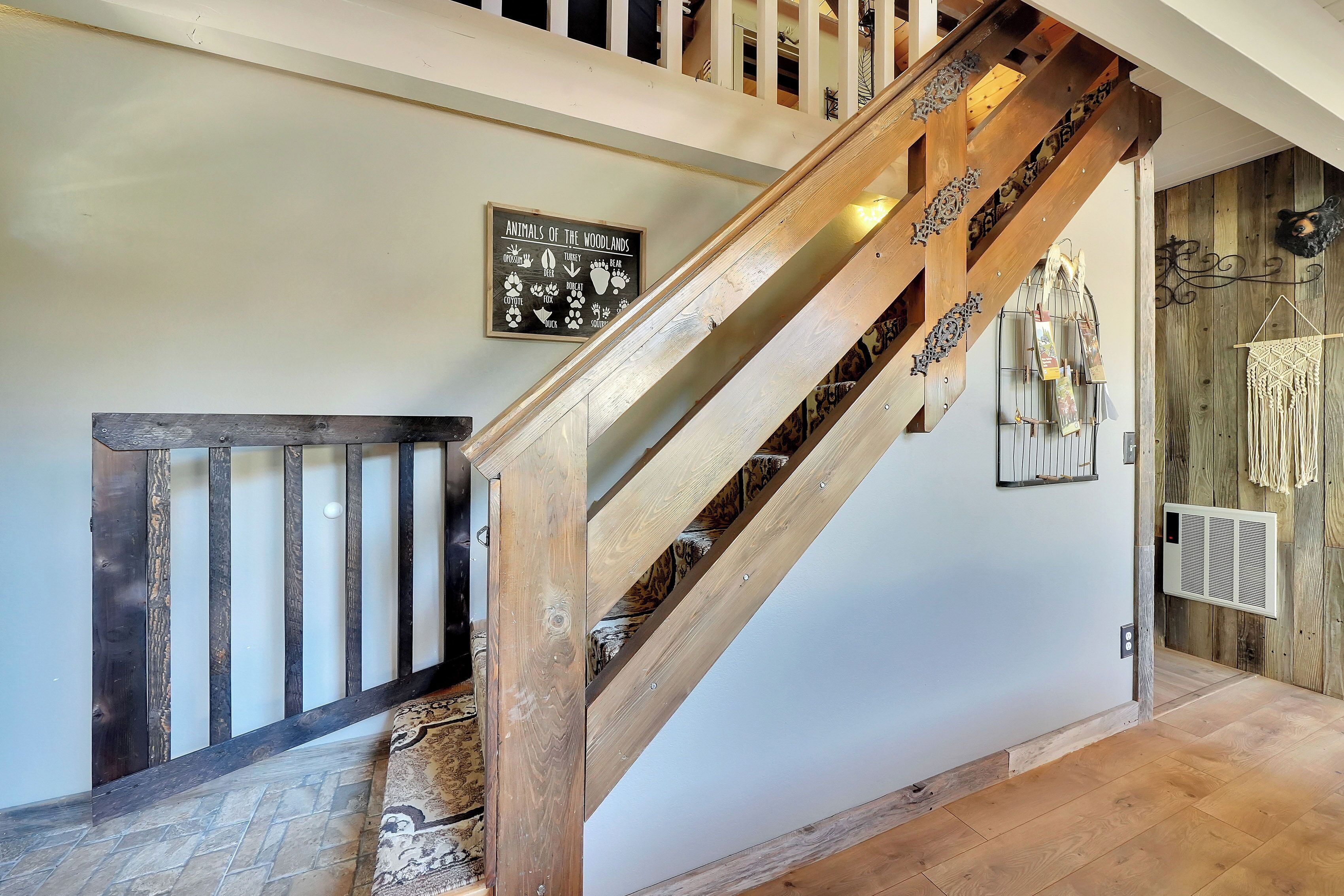 A wooden staircase with a sign about woodland animals, a patterned rug, and a macrame wall hanging.