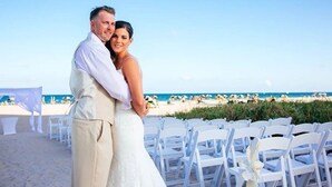 Ceremonia de boda en la playa, con sillas blancas y una vista despejada del océano.