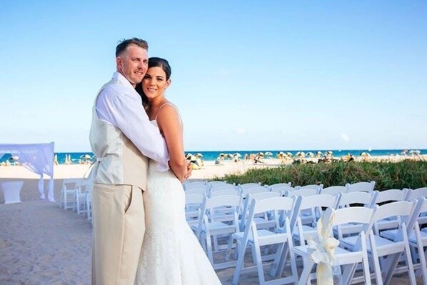 A beach wedding ceremony with white chairs and a clear view of the ocean.