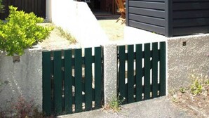 A two-story house with a balcony, a concrete staircase, and a gated entrance.