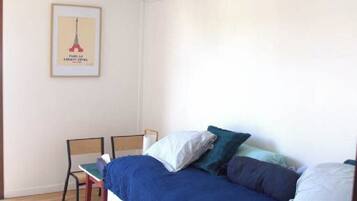 Un dormitorio con cama, dos sillas, un cuadro enmarcado en la pared y suelo de madera.