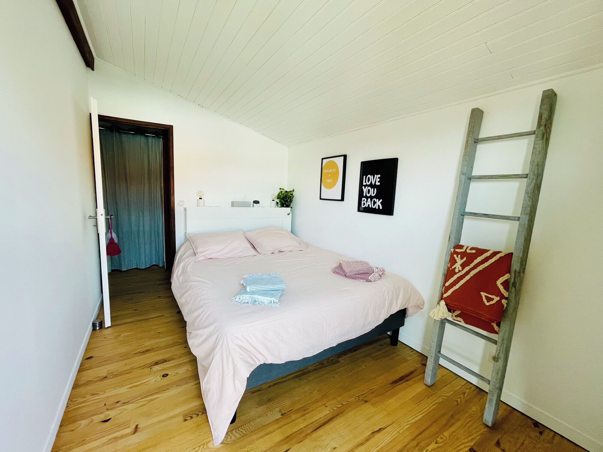 Un dormitorio con una cama, una escalera, una puerta y dos carteles motivacionales en la pared.