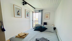A bedroom with a bed, pillows, a folded blanket, and a framed picture on the wall.