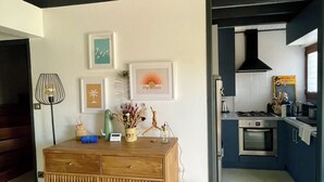 A modern kitchen with a built-in oven, a gas stove, and a microwave. There is a wooden dining table with a vase of flowers and a framed picture on the wall.