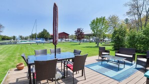 En utomhusveranda med ett bord och stolar, en pool och utsikt över båtar och en byggnad i bakgrunden.