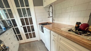 A kitchen with white cabinets, a wooden countertop, a dishwasher, and a tiled backsplash. - Room in house (Lake Andes)