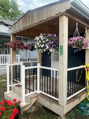 A wooden porch with a white railing, a mailbox, and hanging flower baskets.