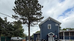 A residential backyard with a blue house, a large tree, outdoor furniture, and a parked van. - Room in house (Lake Andes)