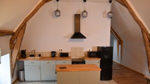 Cozinha com ilha central, vigas de madeira e iluminação pendente.