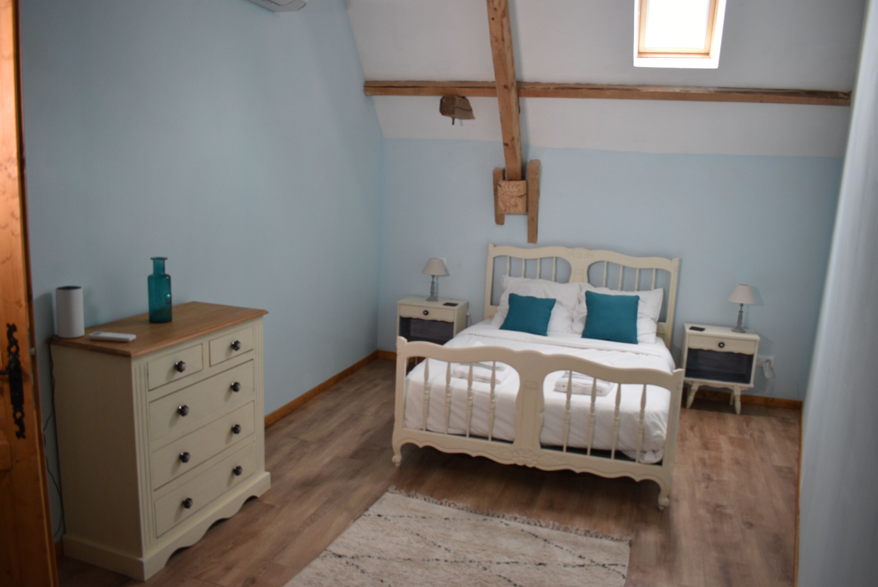 A bedroom with a wooden bed, bedside tables, a dresser, and a window.
