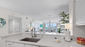 A modern kitchen with white cabinetry, a Bosch dishwasher, a large window, and a view of the city.