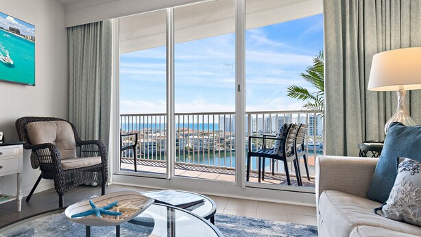 A spacious living room with a balcony overlooking a cityscape and water.