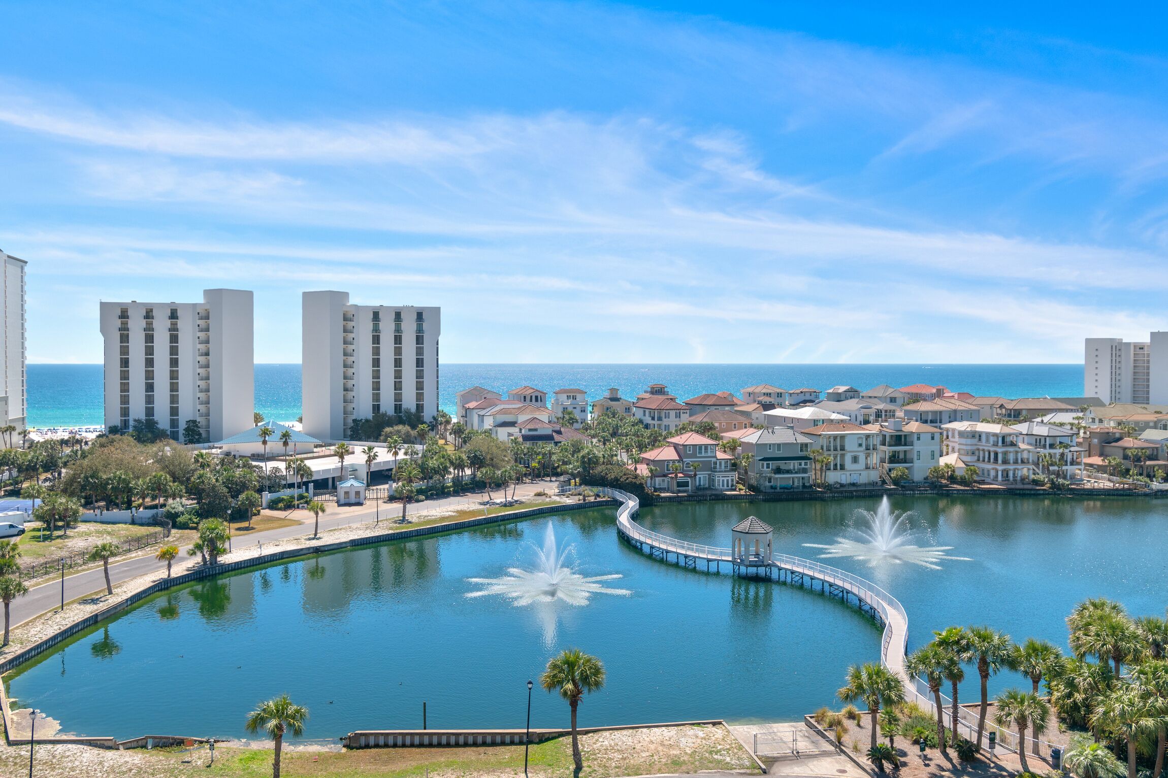 A waterfront hotel with a central water feature, a promenade, and a view of the ocean.