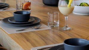 A dining table set with various dishes, glasses, and a bowl of salad. - Capitalia Tres Mares Beach Residences & Marina (Puerto Vallarta)