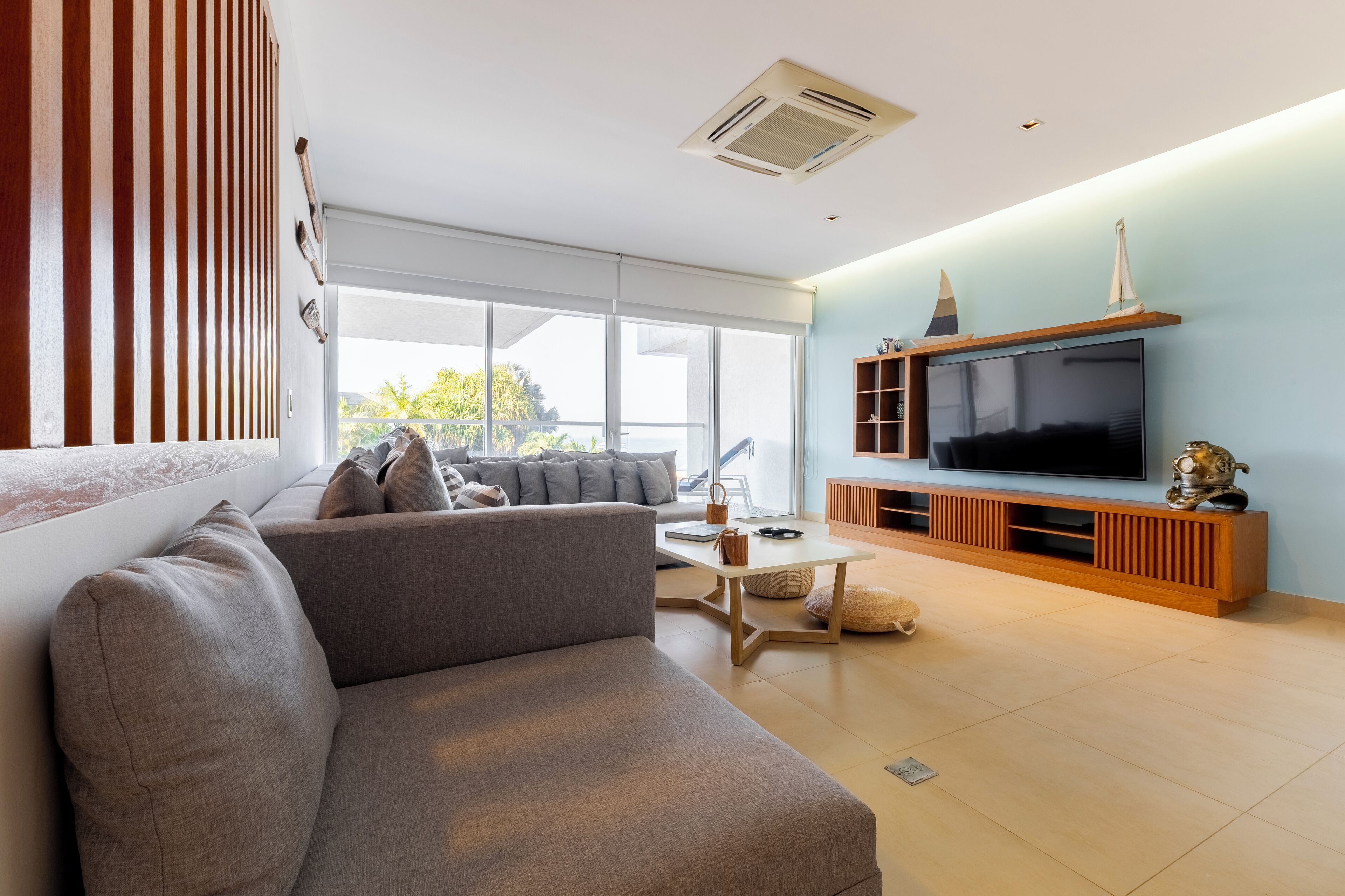 Un salon moderne avec un canapé gris, une table basse et un téléviseur à écran plat posé sur un meuble en bois.