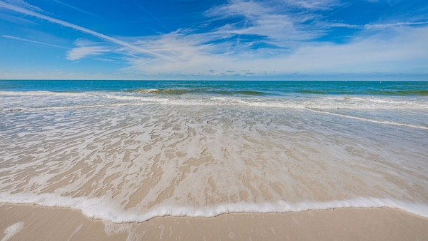 Une plage avec un ciel dégagé et des vagues douces.