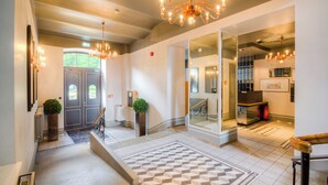 Eine Hotellobby mit Schachbrettmuster-Boden, einer Treppe und einer Kristallleuchter.