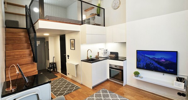 Um apartamento compacto com cozinha compacta, área de refeições e sala de estar com televisão.