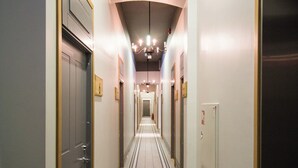 Ein Hotelgang mit Türen an beiden Seiten, einem gefliesten Boden und einer Decke mit eingelassener Beleuchtung.