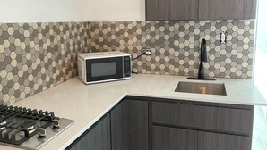 A modern kitchen with dark wood cabinets, a stainless steel sink, a microwave, and a gas stove.