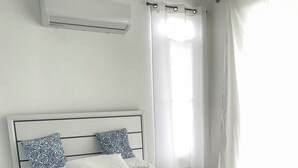 A modern bedroom with a bed, bedside tables, a bedside lamp, and a window with curtains.