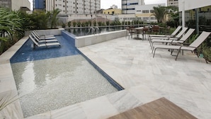 Un espace piscine sur le toit, avec des chaises longues et une petite piscine.