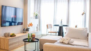 Un salon moderne doté d’un téléviseur à écran plat, d’un canapé, d’une table basse et d’un coin repas avec une table et des chaises.