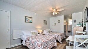 A bedroom with two beds, a ceiling fan, and a small table with chairs.