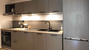 Une cuisine moderne équipée d’un réfrigérateur en acier inoxydable, d’un évier à deux bacs et d’un four encastré.
