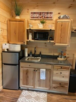 Une cuisine de style rustique, avec des meubles en bois, un réfrigérateur en acier inoxydable, un four à micro-ondes et un évier.
