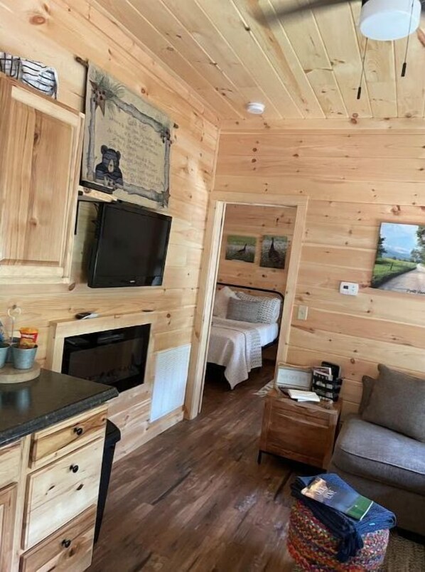 L’intérieur d’un chalet confortable, avec un plancher en bois, un lit, un téléviseur et une petite table.