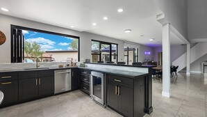 A modern kitchen with dark cabinetry, a built-in oven, and a large window offering a view of the outdoors. - Epic 7BR Escape w/ Pickleball, Pool, Spa & Unmatched Mountain Views (Paradise Valley)