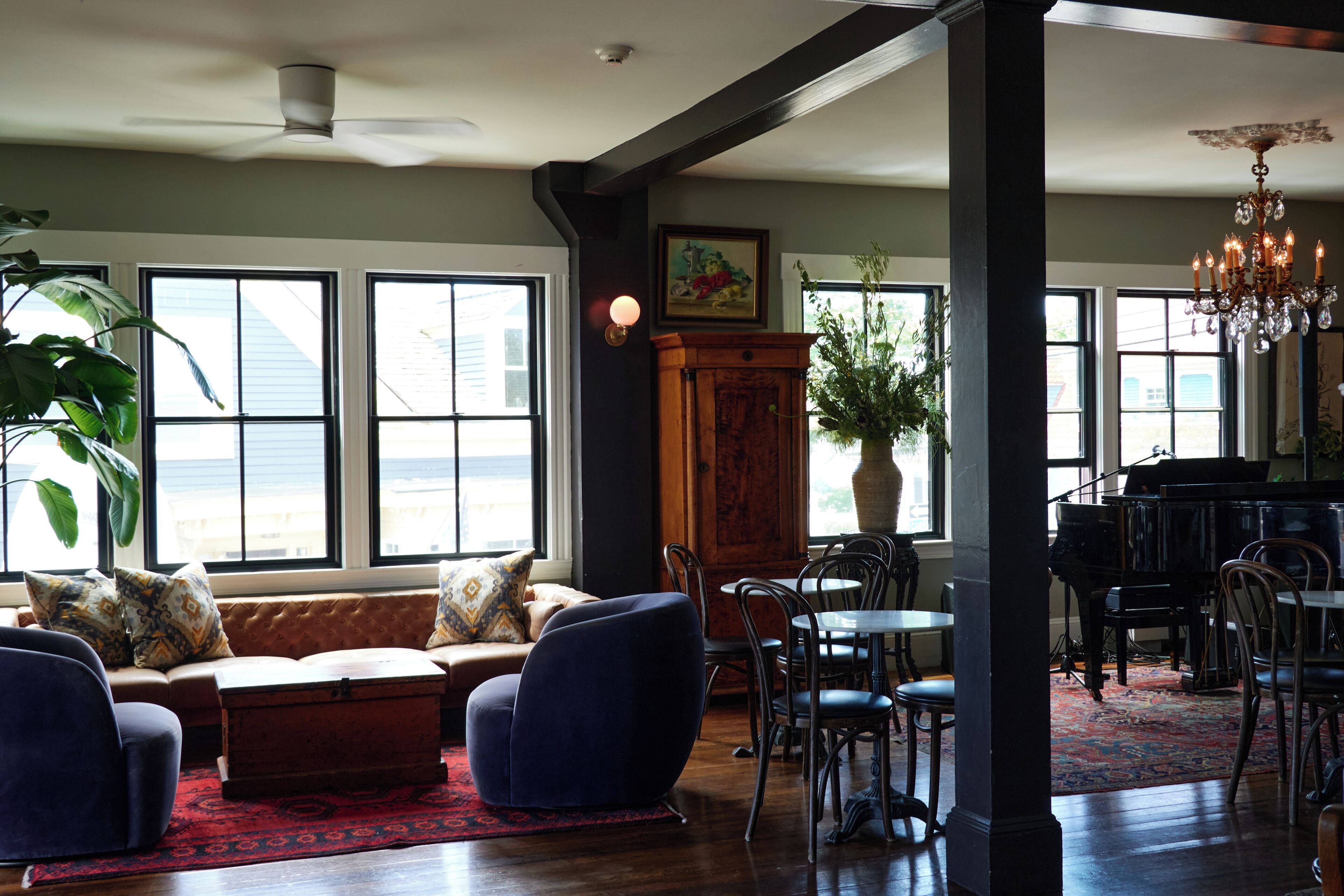 A spacious living area with a piano, seating, and large windows.