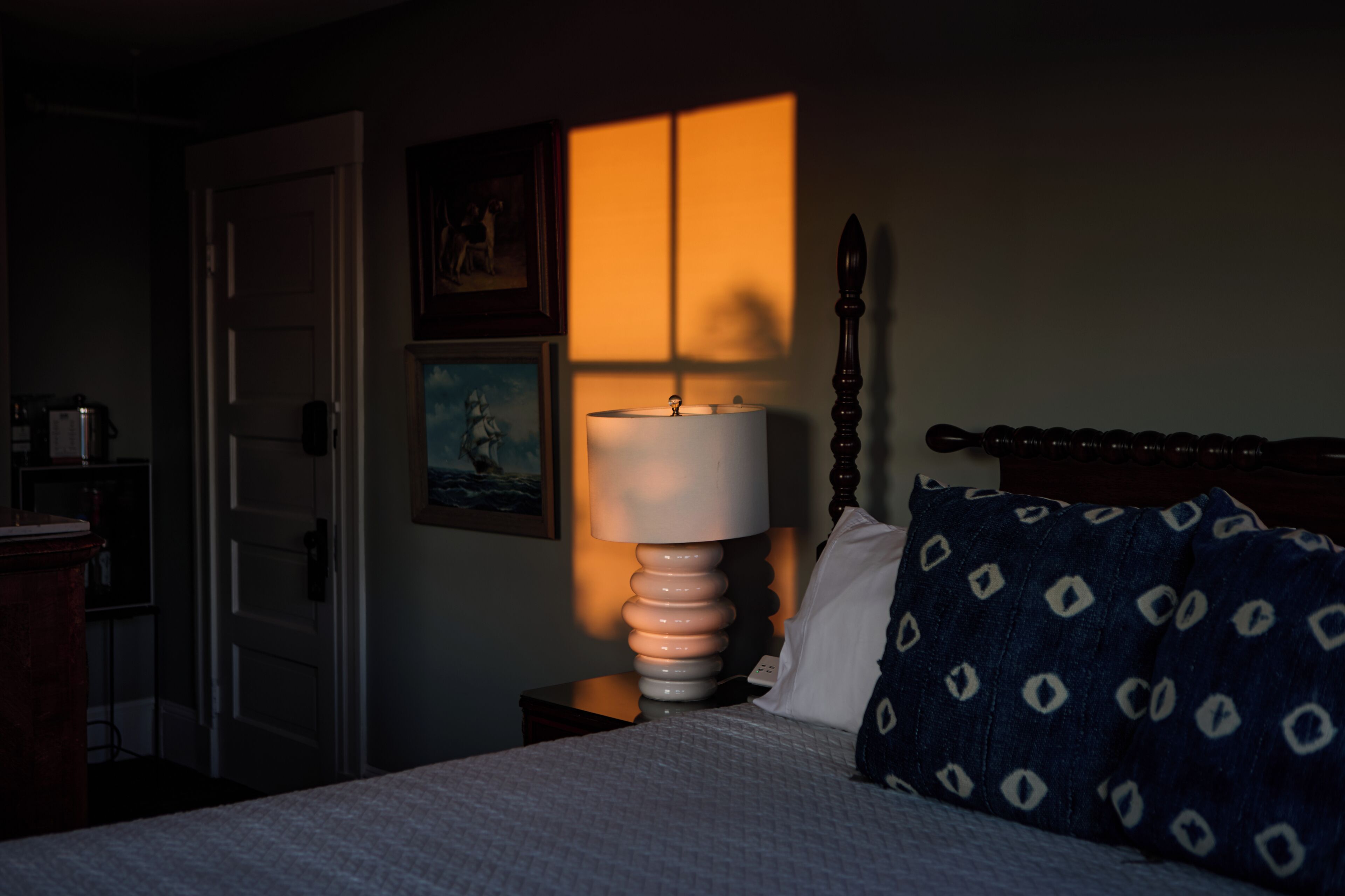 A bedroom with a bed, a nightstand, a lamp, and a door.