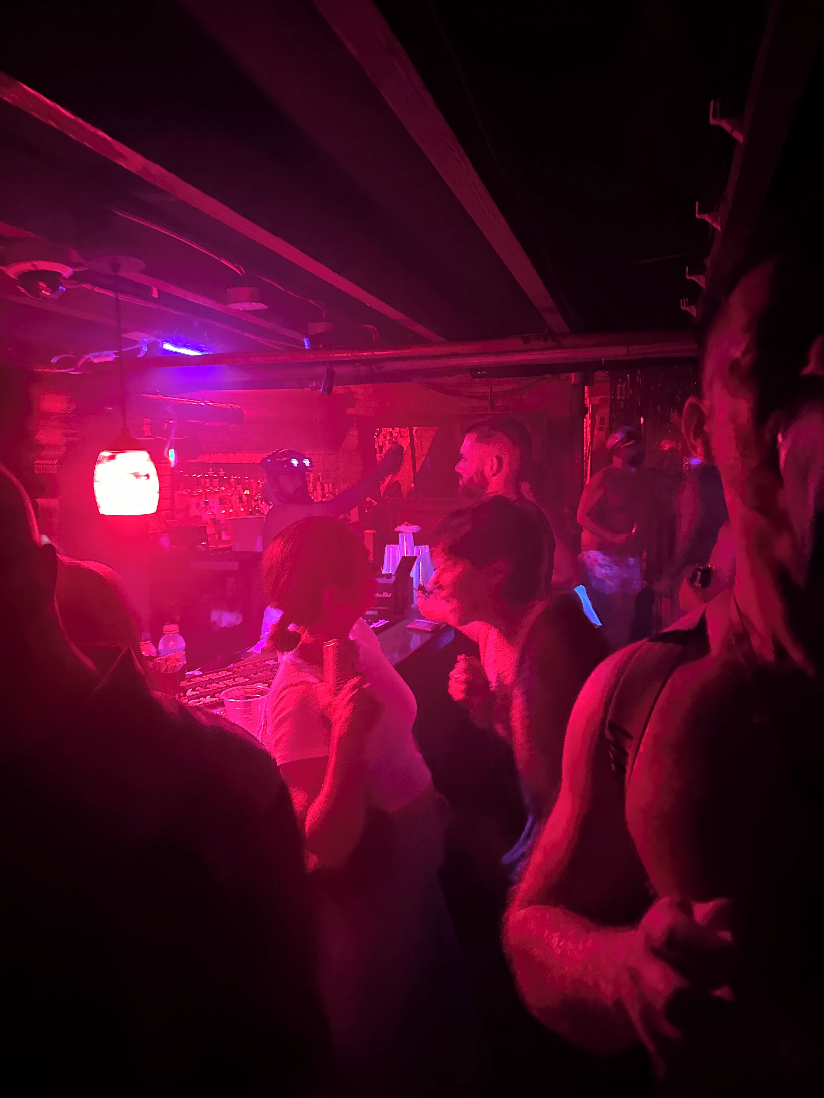 A crowded indoor space with people, a visible television, and a bar area.