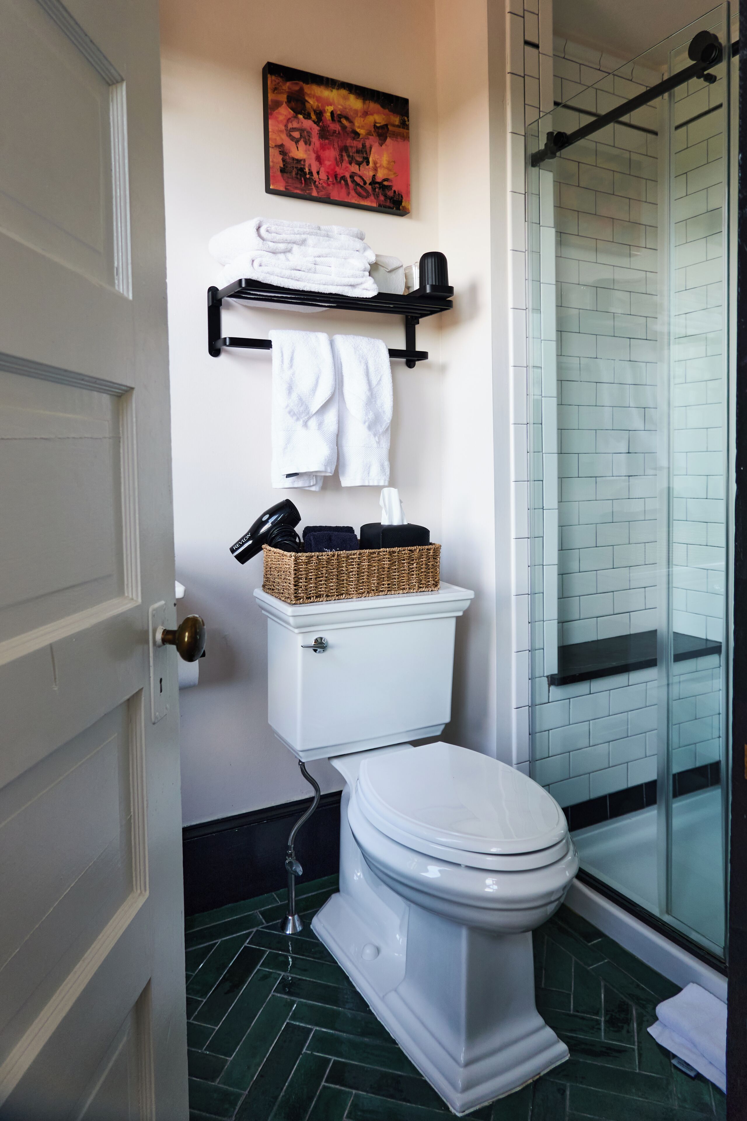 A bathroom with a toilet, a towel rack, a basket, and a shower area.