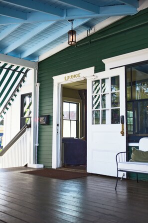 A porch with a bench, a staircase, and a door labeled 'LOUNGE'. - Inn at Gifford House (Provincetown)