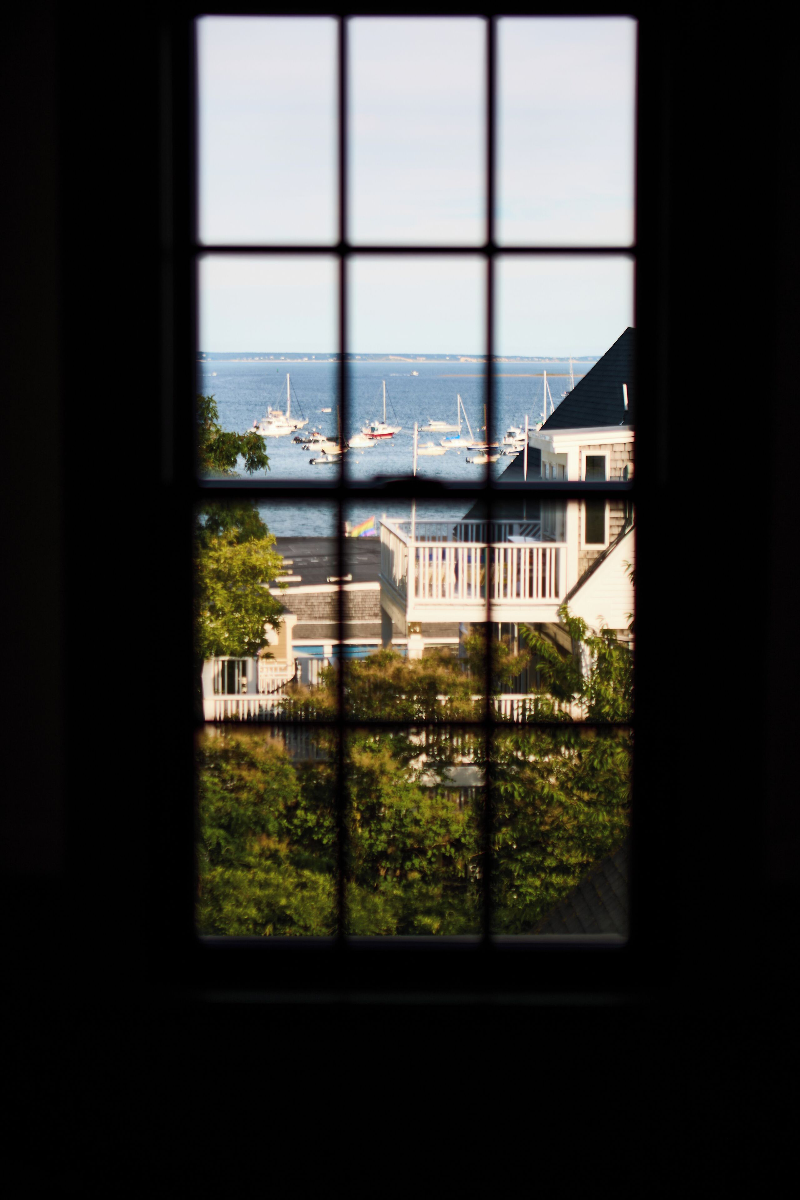 A view through a window with a grid pattern, displaying a marina with boats and a building with a balcony.